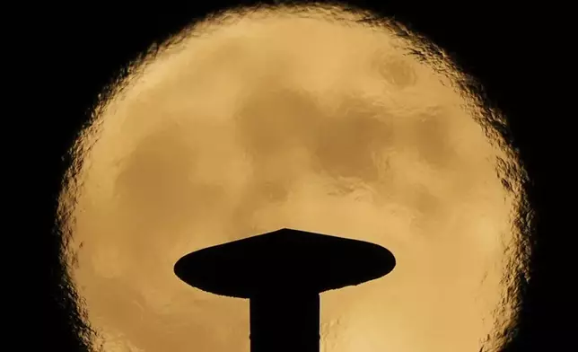 An exhaust pipe from a diesel generator spouts fumes as a supermoon rises in the background, in Beirut, Lebanon, Thursday, Oct. 17, 2024. (AP Photo/Hassan Ammar)