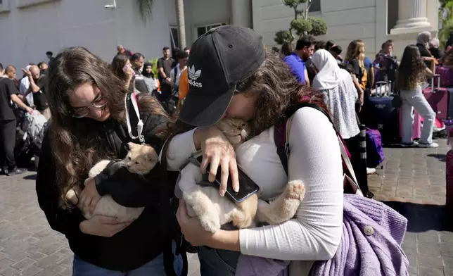 Turkish citizens carry their cats as they wait to board a Turkish navy vessel to be evacuated to Turkey at a gathering point, in Beirut, Lebanon, Wednesday, Oct. 9, 2024. (AP Photo/Hussein Malla)