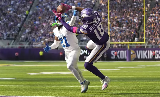 Minnesota Vikings wide receiver Justin Jefferson (18) catches 25-yard touchdown pass as Detroit Lions cornerback Amik Robertson (21) defends during the second half of an NFL football game Sunday, Oct. 20, 2024, in Minneapolis. (AP Photo/Abbie Parr)