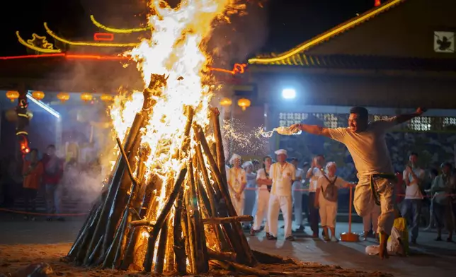 A man set wood on fire to prepare for worshippers to walk barefoot over burning coals during the Nine Emperor Gods festival at a temple in Kuala Lumpur, Malaysia, Monday, Oct. 7, 2024. (AP Photo/Vincent Thian)