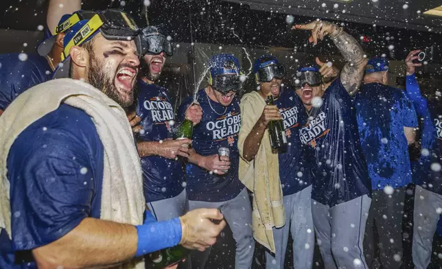 The New York Mets celebrate in the locker room after clinching a playoff berth with a victory in the first baseball game of a doubleheader against the Atlanta Braves, Monday, Sept. 30, 2024, in Atlanta. (AP Photo/Jason Allen)