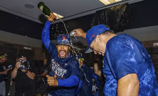 The New York Mets celebrate in the locker room after clinching a playoff berth with a victory in the first game of a doubleheader against the Atlanta Braves, Monday, Sept. 30, 2024, in Atlanta. (AP Photo/Jason Allen)