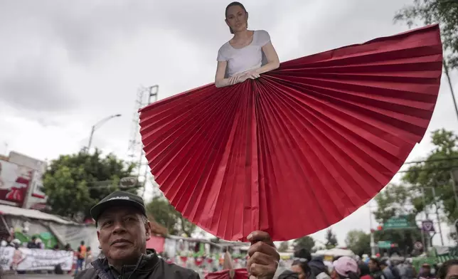 A supporter carries a cutout of President Claudia Sheinbaum during a rally to hear her speak on her inauguration day at the Zocalo, Mexico City's main square, Tuesday, Oct. 1, 2024. (AP Photo/Aurea Del Rosario)