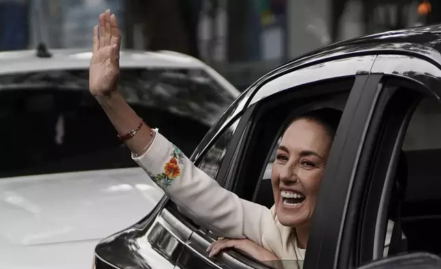 Claudia Sheinbaum waves from the vehicle taking her to Congress where she will be sworn in as president in Mexico City, Tuesday, Oct. 1, 2024. (AP Photo/Aurea Del Rosario)