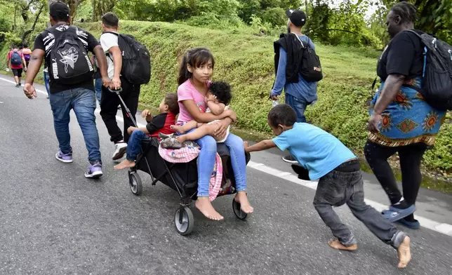 Children ride in a stroller along the Huixtla highway in the state of Chiapas, Mexico, Tuesday, Oct. 22, 2024, as part of a group of migrants hoping to reach the country's northern border and ultimately the United States. (AP Photo/Edgar H. Clemente)