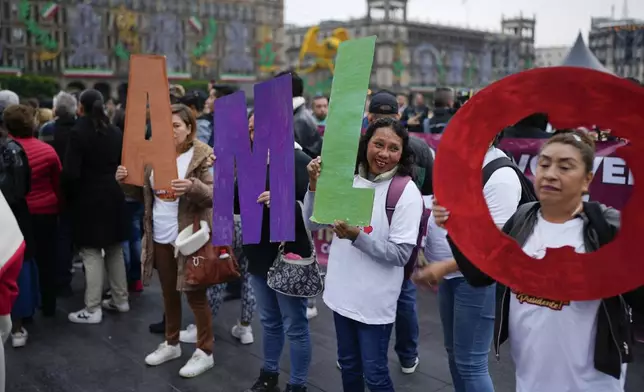 Supporters of Mexican President Andres Manuel Lopez Obrador hold up his initials outside the National Palace where he holds his last morning press conference, "La Mañanera," in Mexico City, Monday, Sept. 30, 2024. (AP Photo/Eduardo Verdugo)