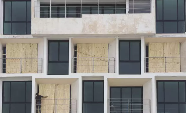 A man boards up an apartment building to protect it from Hurricane Milton, in Progreso, Yucatan state, Mexico, Monday, Oct. 7, 2024. (AP Photo/Martin Zetina)