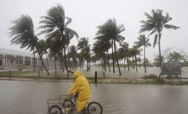 A person rides his bike through a flooded street in the rain as Hurricane Milton passes off the coast of Progreso, Yucatan state, Mexico, Tuesday, Oct. 8, 2024. (AP Photo/Martin Zetina)