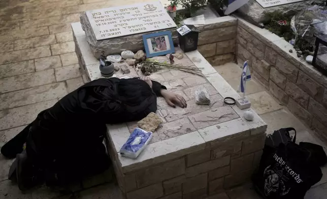 Sara Chen weeps over the grave of her longtime friend, Staff Sergeant Avraham Nerya Cohen, who was killed in action on 7 October. 2023, as Israel marks the one-year anniversary of the Hamas attack on Israel, at the Mount Herzl military cemetery in Jerusalem on Monday, 7 October 2024. (AP Photo/Maya Alleruzzo)