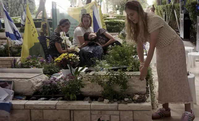 Senai Guedalia tidies the grave of her husband, Sgt. 1st Class Yosef Guedalia, who was killed one year ago at as Israel marks the one-year anniversary of the Hamas attack on Israel, at Mt. Herzl military cemetery in Jerusalem on Monday, Oct. 7, 2024. (AP Photo/Maya Alleruzzo)