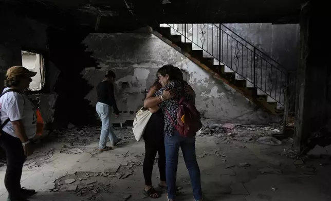 People hug at the house of Maayan and Yuval Bar killed by Hamas, as Israel marks the one-year anniversary of the Hamas attack on Israel, at the Kibbutz Be'eri, an Israeli communal farm on the Gaza border, on Monday, Oct. 7, 2024. (AP Photo/Ohad Zwigenberg)