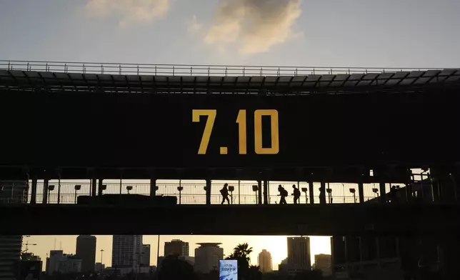 People cross a bridge with the date 7.10, marking the one-year anniversary of the Hamas attack on Israel, in Ramat Gan, Israel, Monday, Oct. 7, 2024. (AP Photo/Oded Balilty)