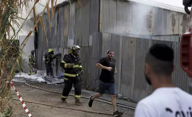 Residents run away as emergency personnel respond after a rocket apparently fired from Gaza hits Kfar Chabad Tel Aviv, Monday, Oct. 7, 2024. (AP Photo/Oded Balilty)