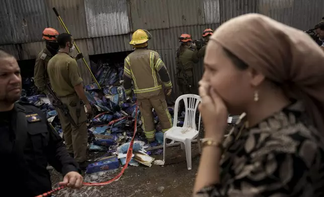 A woman reacts as emergency personnel respond after a rocket apparently fired from Gaza hits Kfar Chabad Tel Aviv, Monday, Oct. 7, 2024. (AP Photo/Oded Balilty)