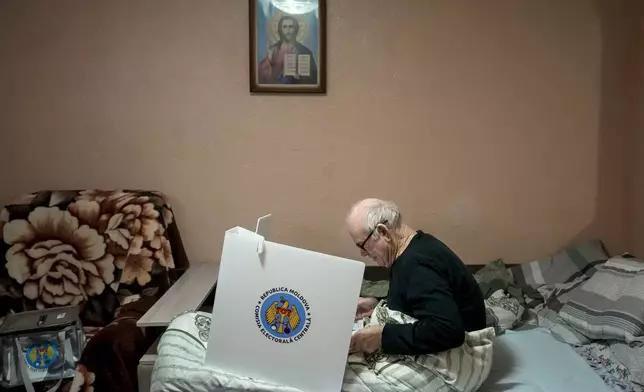 A man casts his vote in a mobile ballot box in the village of Hrusevo, Moldova, Sunday, Oct. 20, 2024, during a presidential election and a referendum on whether to enshrine in the Constitution the country's path to European Union membership. (AP Photo/Vadim Ghirda)