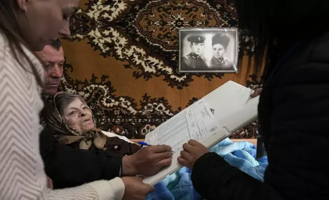 Tatiana, 78 years old, signs her name to receive a stamp to cast her vote in a mobile ballot box in the village of Hrusevo, Moldova, Sunday, Oct. 20, 2024, during a presidential election and a referendum on whether to enshrine in the Constitution the country's path to European Union membership. (AP Photo/Vadim Ghirda)