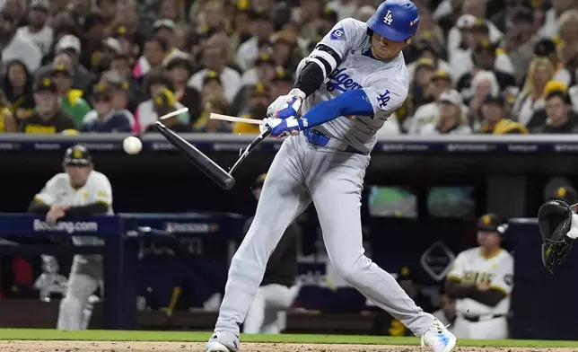 Los Angeles Dodgers' Shohei Ohtani breaks his bat as he singles during the third inning in Game 3 of a baseball NL Division Series against the San Diego Padres, Tuesday, Oct. 8, 2024, in San Diego. (AP Photo/Gregory Bull)