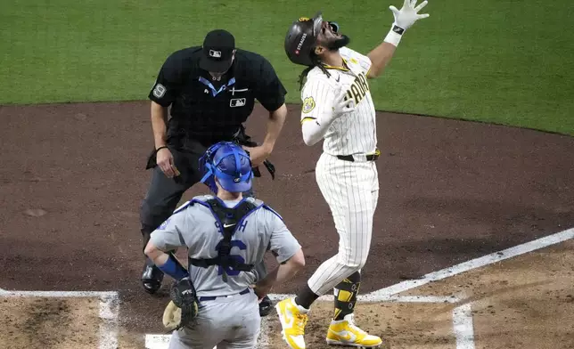 San Diego Padres' Fernando Tatis Jr., right, celebrates as he scores after hitting a two-run home run as Los Angeles Dodgers catcher Will Smith stands at the plate during the second inning in Game 3 of a baseball NL Division Series, Tuesday, Oct. 8, 2024, in San Diego. (AP Photo/Ashley Landis)