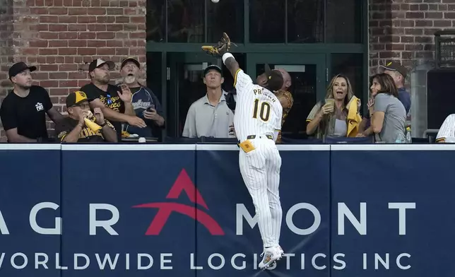 San Diego Padres left fielder Jurickson Profar reaches over the wall but cannot catch a home run ball from Los Angeles Dodgers' Mookie Betts during the first inning in Game 3 of a baseball NL Division Series Tuesday, Oct. 8, 2024, in San Diego. (AP Photo/Ashley Landis)