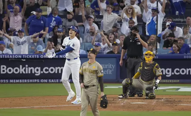 Los Angeles Dodgers' Shohei Ohtani, middle left, drops his bat while watching his three-run home run off San Diego Padres starting pitcher Dylan Cease, foreground, during the second inning in Game 1 of baseball's NL Division Series, Saturday, Oct. 5, 2024, in Los Angeles. (AP Photo/Mark J. Terrill)