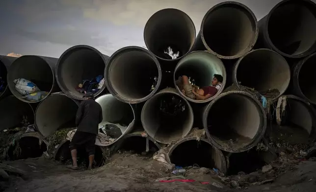 A man sits inside a concrete pipe meant for the municipal use after his shelter was swept away by the flooding Bagmati River in Kathmandu, Nepal, on Tuesday, Oct. 1, 2024. (AP Photo/Niranjan Shrestha)