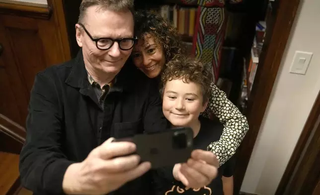 Nobel prize winner in Economics, James A. Robinson makes a selfie for the Nobel Foundation with his wife, Dr. Maria Angelica Bautista, and their son Adrian at their home in the Hyde Park neighborhood of Chicago, Monday, Oct. 14, 2024. (AP Photo/Charles Rex Arbogast)