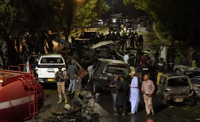 Security officials examine the site of an explosion that caused injures and destroyed vehicles outside Karachi airport, Pakistan, early Monday, Oct. 7, 2024. (AP Photo/Fareed Khan)