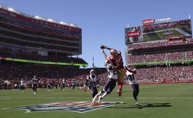 San Francisco 49ers tight end George Kittle (85) catches a touchdown pass between New England Patriots safety Dell Pettus, middle left, and cornerback Jonathan Jones (31), as cornerback Marcus Jones (25) watches, during the first half of an NFL football game in Santa Clara, Calif., Sunday, Sept. 29, 2024. (AP Photo/Jed Jacobsohn)