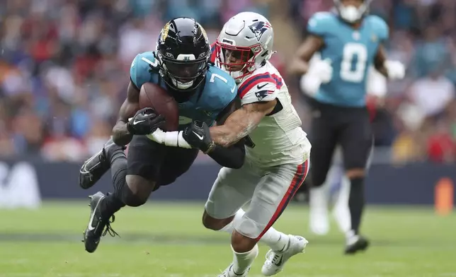 Jacksonville Jaguars wide receiver Brian Thomas Jr. (7) is tackled by New England Patriots cornerback Christian Gonzalez (0) during the first half of an NFL football game, Sunday, Oct. 20, 2024, in London. (AP Photo/Ian Walton)