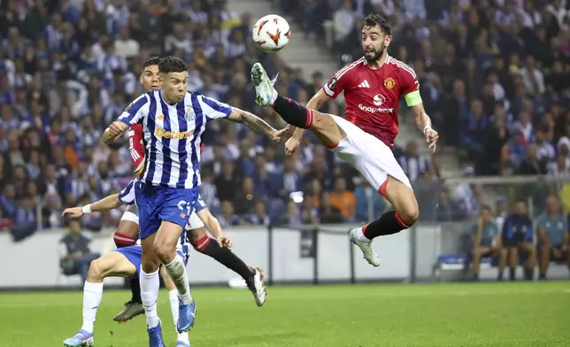 Manchester United's Bruno Fernandes, right, reaches for the ball too high and close to the head of Porto's Nehuen Perez to see a second yellow card and be sent off, during a Europa League opening phase soccer match between FC Porto and Manchester United at the Dragao stadium in Porto, Portugal, Thursday, Oct. 3, 2024. (AP Photo/Luis Vieira)