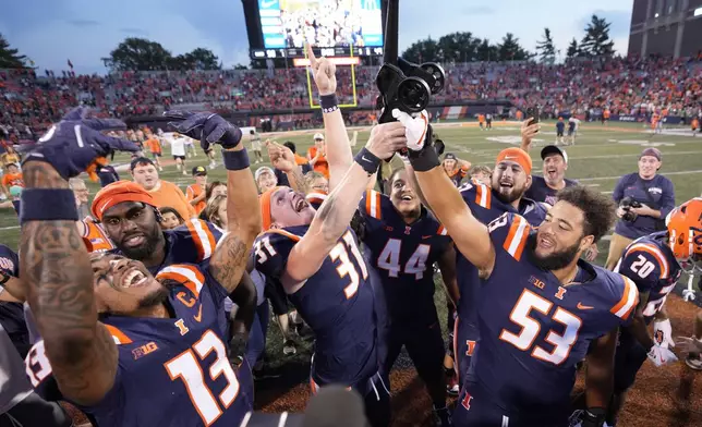 Illinois wide receiver Pat Bryant (13) Declan Duley (31) and Devin Hale (53) celebrate with the Purdue cannon after the team's 50-49 overtime win over Purdue in an NCAA college football game Saturday, Oct. 12, 2024, in Champaign, Ill. (AP Photo/Charles Rex Arbogast)