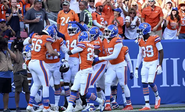 Teammates surround Denver Broncos cornerback Riley Moss (21) after his interception intended for Las Vegas Raiders wide receiver Tre Tucker during the second half of an NFL football game, Sunday, Oct. 6, 2024, in Denver. (AP Photo/Geneva Heffernan)