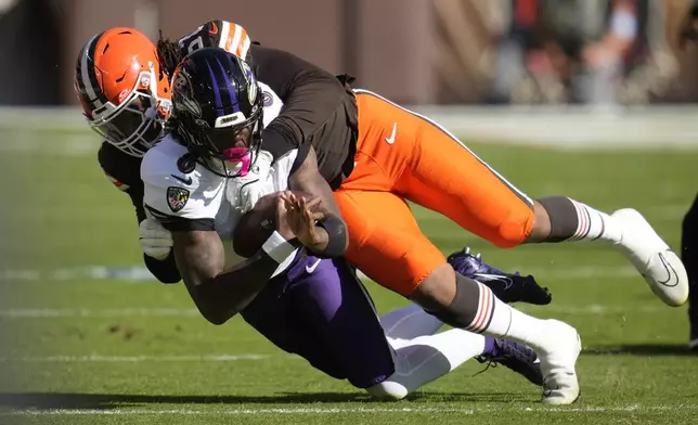 Baltimore Ravens quarterback Lamar Jackson (8) is tackled by Cleveland Browns defensive end Isaiah McGuire (57) during the first half of an NFL football game in Cleveland, Sunday, Oct. 27, 2024. (AP Photo/Sue Ogrocki)