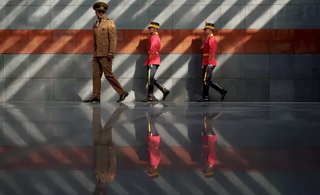 Romanian serviceman walk after laying flower wreaths inside the Holocaust memorial, backdropped by names of victims engraved in rusty metal plates, during the National Holocaust Remembrance Day commemorations in Bucharest, Romania, Wednesday, Oct. 9, 2024, the date when, in 1941, the deportations of Jews and Roma began in the country. (AP Photo/Andreea Alexandru)