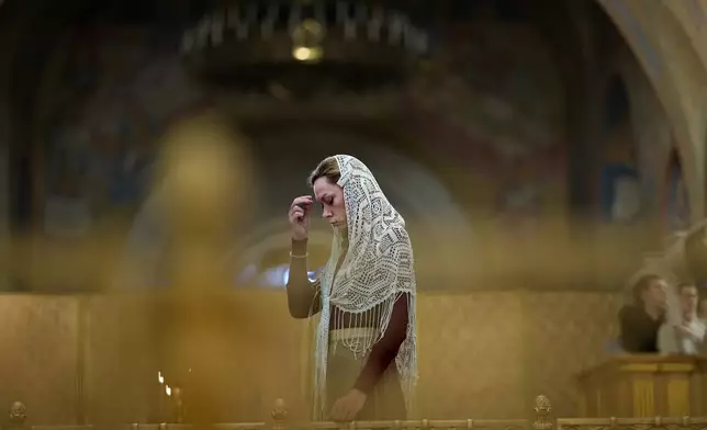 A woman crosses herself attending a memorial service that commemorates the victims of Soviet-era purges as part of 'the Day of Remembrance for the Victims of Political Repressions' at the Cathedral of Christ the Saviour in Moscow, Russia, Wednesday, Oct. 30, 2024. (AP Photo/Alexander Zemlianichenko)