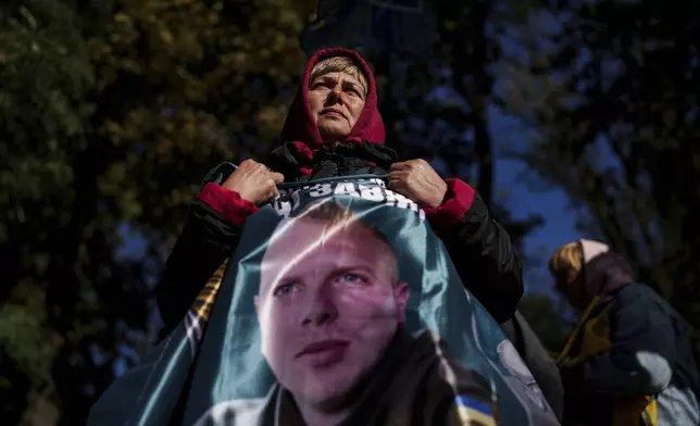 Svetlana holds a flag with a photo of her son Andrii Savchuk, a Ukrainian officer of the 36th marine brigade, during a gathering in support of soldiers who defended Mariupol and are still in Russian captivity after two and half years, in Kyiv, Ukraine, Wednesday, Oct. 9, 2024. (AP Photo/Evgeniy Maloletka)