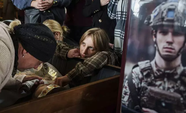 Relatives cry over the coffin of Ihor Kusochek, Ukrainian soldier of the Azov brigade who was killed at the frontline in Toretsk, during his funeral ceremony in Bobrovytsia, Chernihiv region, Ukraine, Friday Oct. 4, 2024. (AP Photo/Evgeniy Maloletka)