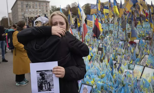 People react during a nationwide minute of silence in memory of fallen soldiers, who defended their homeland in war with Russia, on Defenders Day at the improvised war memorial in Independence square in Kyiv, Ukraine, Tuesday, Oct. 1, 2024. (AP Photo/Efrem Lukatsky)