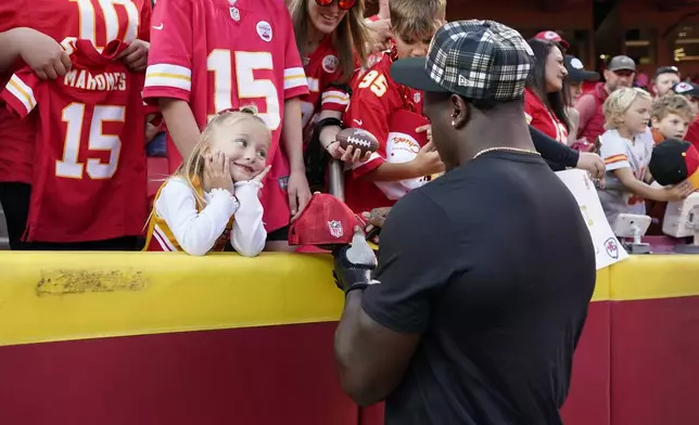 New Orleans Saints linebacker Willie Gay Jr. signs autographs for a young fan before the start of an NFL football game against the Kansas City Chiefs Monday, Oct. 7, 2024, in Kansas City, Mo. (AP Photo/Ed Zurga)