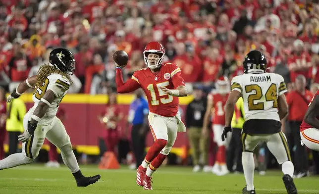 Kansas City Chiefs quarterback Patrick Mahomes, center, runs with the ball as New Orleans Saints defensive end Chase Young and safety Johnathan Abram (24) defend during the second half of an NFL football game Monday, Oct. 7, 2024, in Kansas City, Mo. (AP Photo/Charlie Riedel)