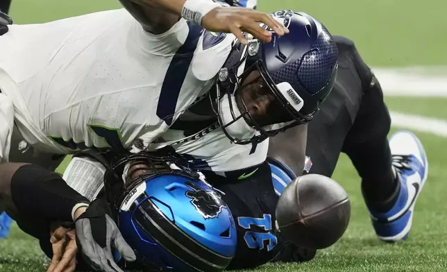 Detroit Lions defensive end Levi Onwuzurike (91) sacks Seattle Seahawks quarterback Geno Smith (7) and forces a fumble but is recovered by Smith during the second half of an NFL football game, Monday, Sept. 30, 2024, in Detroit. (AP Photo/Paul Sancya)