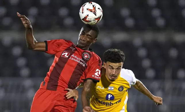 Midtjylland's Denil Castillo, left, and Maccabi Tel Aviv's Stav Lemkin jump for the ball during the Europa League opening phase soccer match between Maccabi Tel Aviv and Midtjylland, at the Partizan stadium, in Belgrade, Serbia, Thursday, Oct. 3, 2024. (AP Photo/Darko Vojinovic)