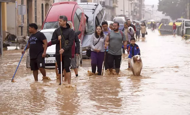 People walk through flooded streets in Valencia, Spain, Wednesday, Oct. 30, 2024. (AP Photo/Alberto Saiz)