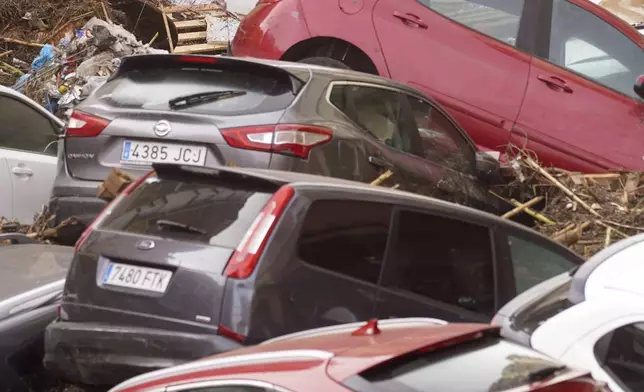 Residents look at cars piled up after being swept away by floods in Valencia, Spain, Wednesday, Oct. 30, 2024. (AP Photo/Alberto Saiz)