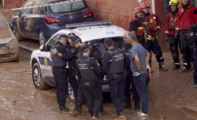 Members of the local police react to the news of one of their colleagues who died in the floods in Valencia, Spain, Thursday, Oct. 31, 2024. (AP Photo/Alberto Saiz)