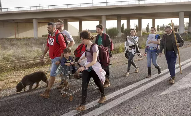 People walk along the road after leaving their homes flooded by the floods in Paiporta, near Valencia, Spain on Wednesday, Oct. 30, 2024. (AP Photo/Alberto Saiz)