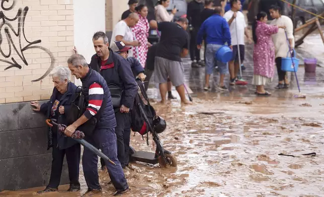 People walk through flooded streets in Valencia, Spain, Wednesday, Oct. 30, 2024. (AP Photo/Alberto Saiz)