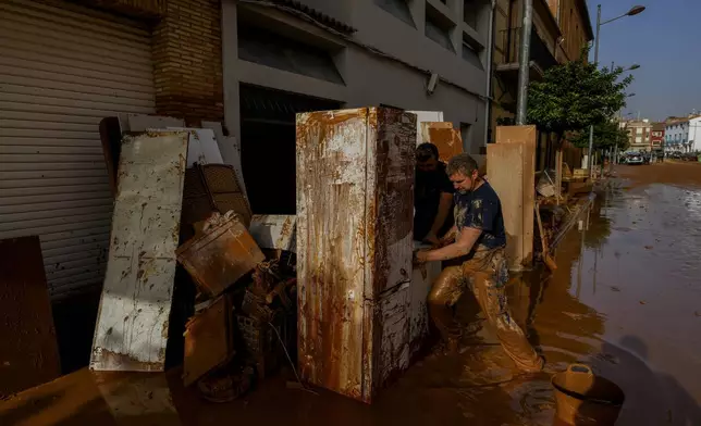 A man cleans his house hit by floods in Utiel, Spain, Wednesday, Oct. 30, 2024. (AP Photo/Manu Fernandez)