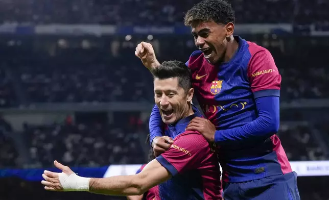 Barcelona's Robert Lewandowski celebrates after scoring his side's second goal with Lamine Yamal, right, during a Spanish La Liga soccer match between Real Madrid and Barcelona at the Santiago Bernabeu stadium in Madrid, Spain, Saturday, Oct. 26, 2024. (AP Photo/Manu Fernandez)