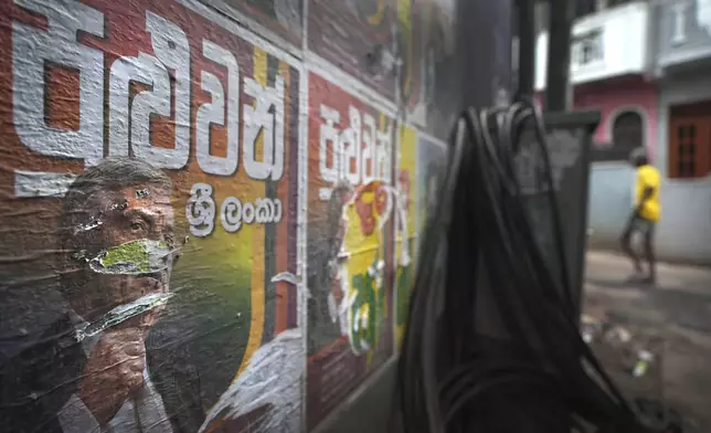 A man walks past torn election posters of President Ranil Wickremesinghe at a street in Colombo, Sri Lanka, Sunday, Sept. 22, 2024.(AP Photo/Rajesh Kumar Singh)